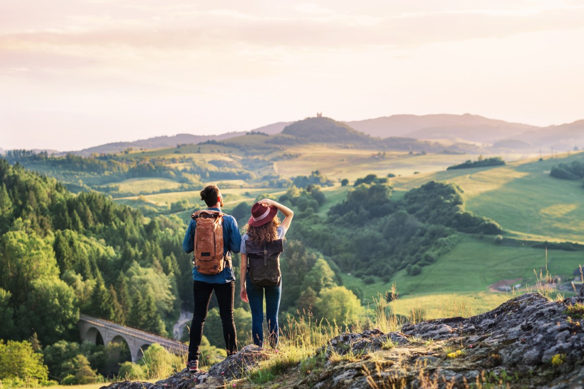 Rear view of young tourist couple travellers hiking in nature resting